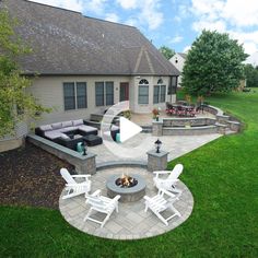 an outdoor patio with seating and fire pit in the middle of it, surrounded by green grass