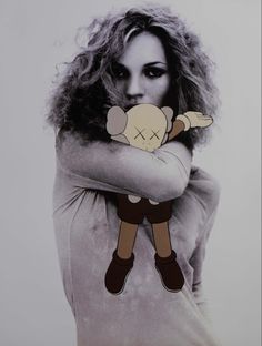 a woman with her arms crossed holding a stuffed animal in front of her face and looking at the camera