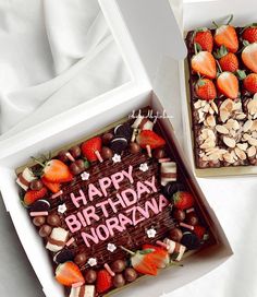 two birthday cakes with strawberries and nuts in a box