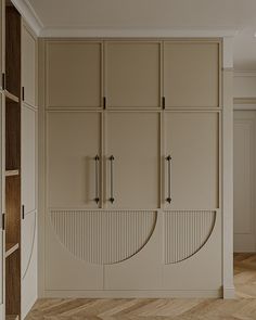 an empty room with beige cupboards and wooden flooring, along with white walls