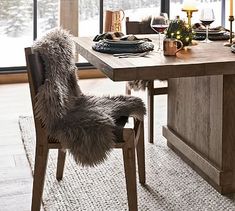 a dining room table with chairs and a christmas tree in the window sill next to it