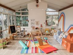 a child's playroom filled with lots of toys and furniture in front of large windows