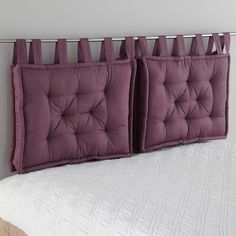 two purple pillows hanging on the side of a bed