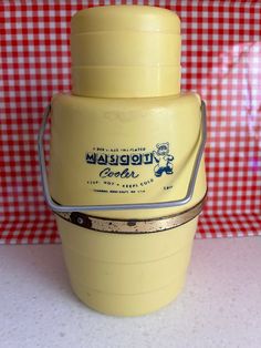 a yellow plastic container sitting on top of a table next to a red and white checkered wall