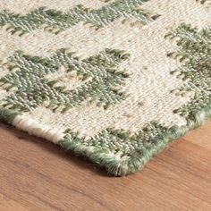 a close up view of a rug on a wooden floor with green and white colors