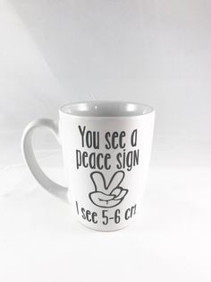 a white coffee cup with the words you see a peace sign on it's side