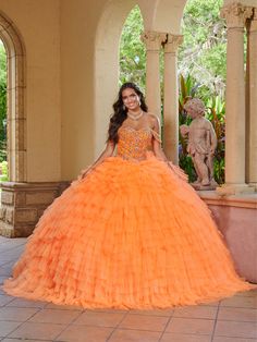 a woman in an orange ball gown posing for the camera