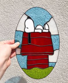 a hand holding a piece of stained glass with a cartoon character on the front and side