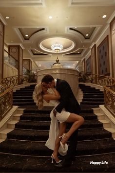 a man and woman kissing on the steps of a staircase in an elegant hotel lobby