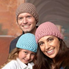 a man and two girls wearing knitted hats smiling at the camera while standing next to each other