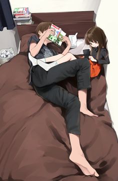 two people sitting on a bed with books in their hands and one person laying down