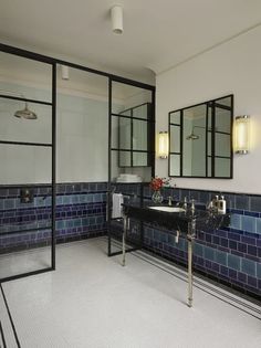 a bathroom with two sinks, mirrors and blue tiles on the wall in it's corner