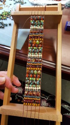 a person is weaving beads on a wooden stand