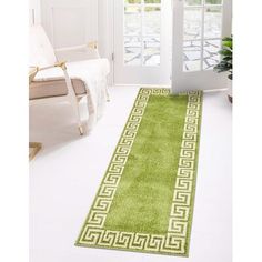 a green rug with white greek border on the floor next to a chair and door