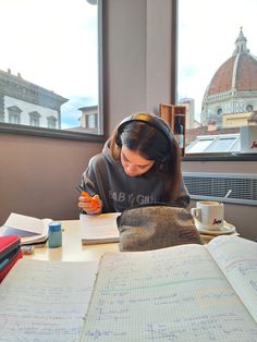 a woman sitting at a table in front of an open book with writing on it