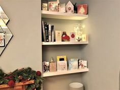 christmas decorations are displayed on shelves in the corner of a room with a mirror above it