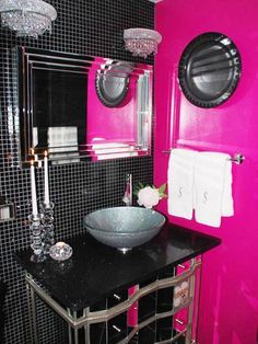 a bathroom with black and pink walls, white towels and chandelier above the sink