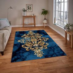 a blue area rug with gold designs on the floor in front of a couch and window