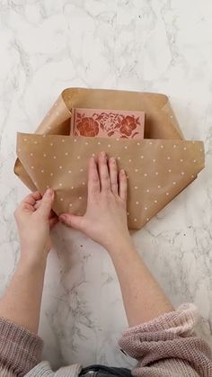 a person is wrapping up a brown paper bag with white polka dots on it,