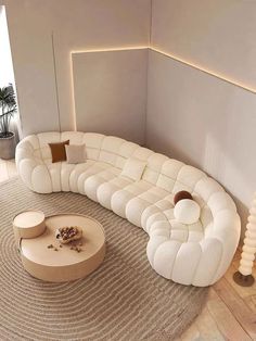 a large white couch sitting on top of a wooden floor next to a round table