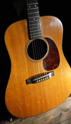 an acoustic guitar sitting on top of a wooden table