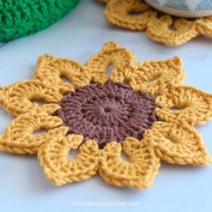 two crocheted flowers sitting next to each other on a white counter top,