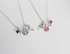 two necklaces with charms on them sitting next to each other