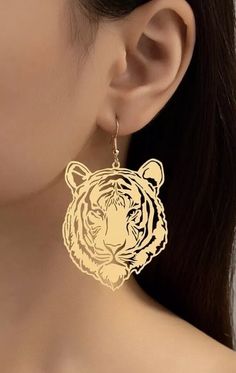 a woman wearing gold earrings with a tiger design on it's ear and the back of her head