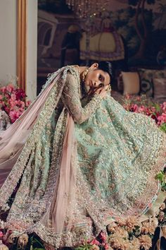 a woman in a blue and pink wedding dress posing for the camera with her arms behind her head