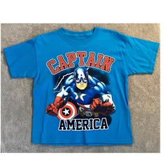 Show Off Your Love For The Avengers With This Stylish Jersey Look T-Shirt Featuring Captain America! Made For Boys, This Marvel-Themed Shirt Is Perfect For Any Young Fan Of The Franchise. The Blue Shirt Has A Jersey-Style Design And Is Made Of High-Quality Materials That Make It Durable And Comfortable To Wear. The Shirt Features Captain America's Iconic Shield And Is Available In Size L. It Is Perfect For Any Occasion, Whether It's A Casual Day Out With Friends Or A Superhero-Themed Party. Don' Blue Character Print T-shirt For Summer, Blue Cotton Top With Cartoon Print, Light Blue Crew Neck T-shirt With Character Print, Blue Graphic Tee With Character Print, Blue Short Sleeve Shirt With Cartoon Print, Blue Character Print Graphic Tee, Blue Short Sleeve Themed Tops, Fun Blue Shirt With Cartoon Print, Blue Crew Neck Tops With Character Print