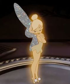 the tinkerbell fairy is standing on top of a round object with her arms behind her back