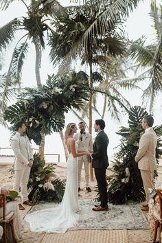 a bride and groom are getting married under palm trees