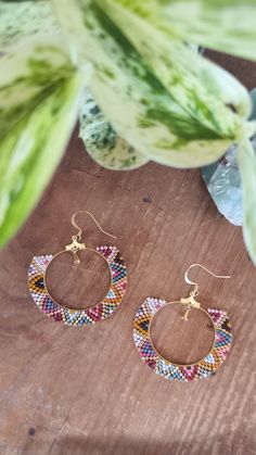 a pair of earrings sitting on top of a wooden table next to a potted plant