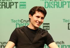 a young man sitting in front of a green wall with the words techcrunch disrupt on it