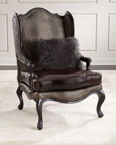 an ornate chair with a fur pillow on it's back and arm rests in front of a paneled wall