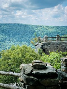 a scenic view of mountains and trees from the top of a hill with a wooden fence