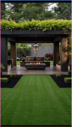 an outdoor living area with grass, couch and fire pit in the middle of it