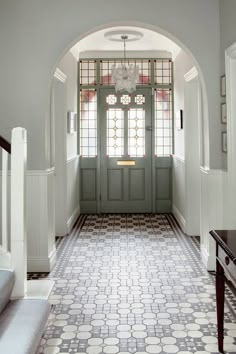 an arched doorway with stained glass windows and tiled flooring is flanked by a staircase