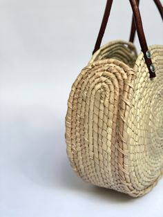 Sustainably Handwoven Straw Circle Bag The Mia Straw Circle Bag is lightweight and durable. This small-size bag will hold all of your essential items. It's the perfect bag for cruising around town. These bags are individually hand-woven with sustainable palm leaves and have naturally tanned leather handles. Thoughtfully designed and ethically made by artisans in Guerrero, Mexico, in a fair trade environment. Each bag is unique and may vary in size, and color, and may have small imperfections. De Natural Woven Leather Top Handle Bag, Summer Woven Leather Bag With Round Handle, Vacation Shoulder Bag With Woven Leather And Round Handle, Summer Straw Bag With Woven Leather And Round Handle, Everyday Woven Leather Beach Bag With Double Handle, Everyday Double Handle Woven Leather Beach Bag, Everyday Crochet Bag With Open Weave, Eco-friendly Palm Leaf Bag With Open Weave, Natural Color Basket Shaped Woven Leather Bag