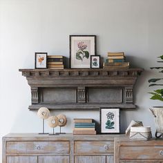 an old dresser with some books and pictures on the top, in front of a white wall