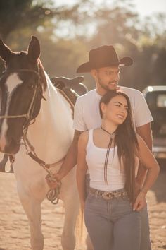 a man and woman standing next to a horse