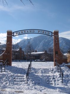 an entrance to a campus with snow on the ground and mountains in the background,