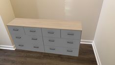 a white and grey dresser in a room with hard wood flooring next to a wall