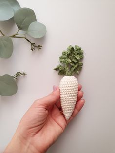 a hand is holding a tiny crocheted vegetable