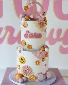 a three tiered cake decorated with flowers and smiley faces on it's sides