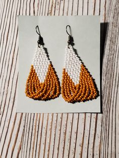 beaded earrings with orange and white tears are displayed on a piece of paper