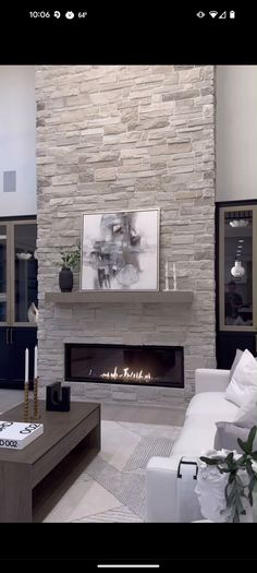 a living room filled with furniture and a fire place in front of a stone wall