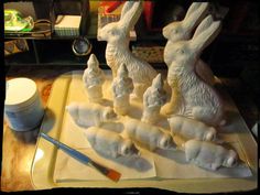 a group of white rabbits sitting on top of a counter next to a paintbrush