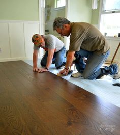 two men working on a wood floor in a house