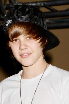 a young boy wearing a black hat and white t - shirt with a chain around his neck